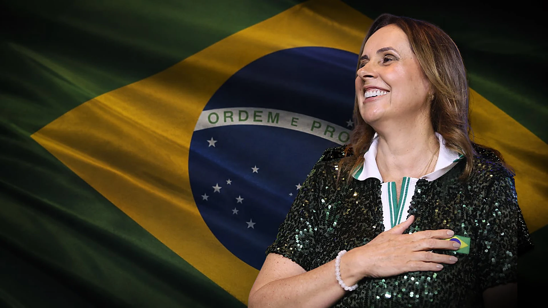 Maria Amélia com a mão no coração diante da bandeira do Brasil
